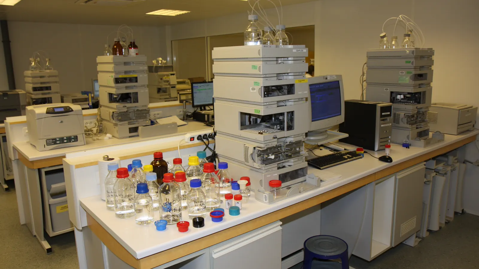 Quality-control laboratory with HPLC systems and solvent bottles, the kind of setup used to test peptide purity